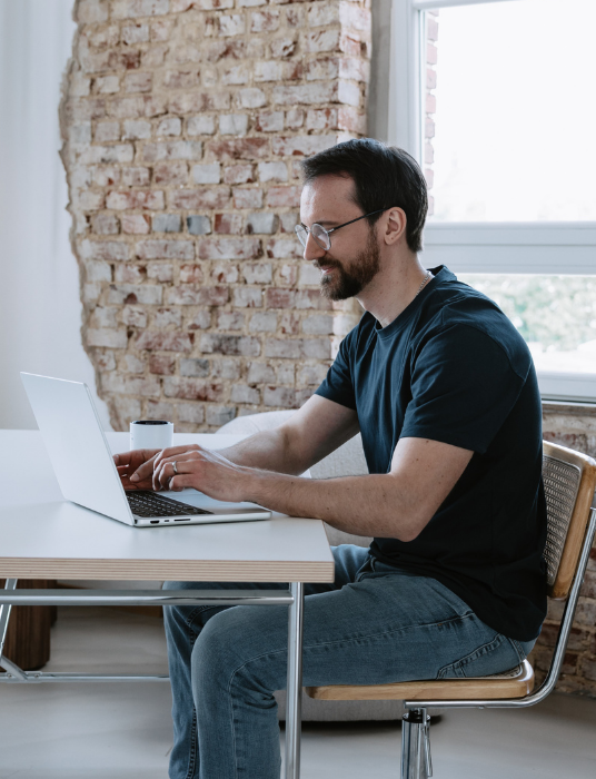Ein junger Mann sitzt mit leicht frustrierten Gesichtsausdruck vor dem Laptop. Er versucht die eingehenden Buchungen seines Gruppenhauses manuell zu bearbeiten.